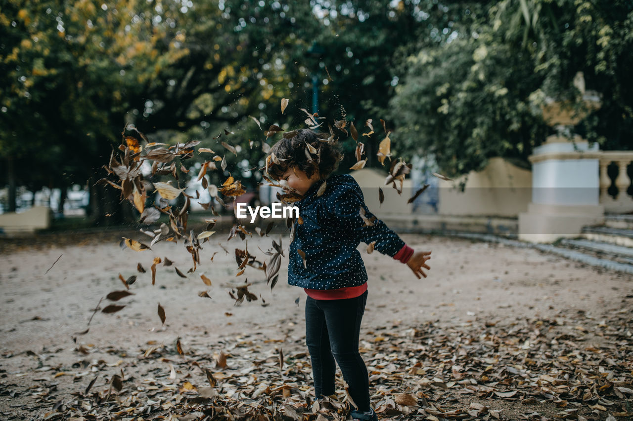 Full length of girl playing with fall leaves