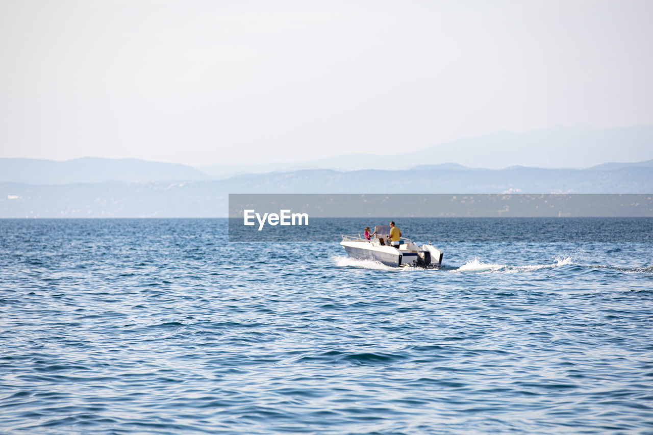 PEOPLE SAILING ON SEA AGAINST CLEAR SKY