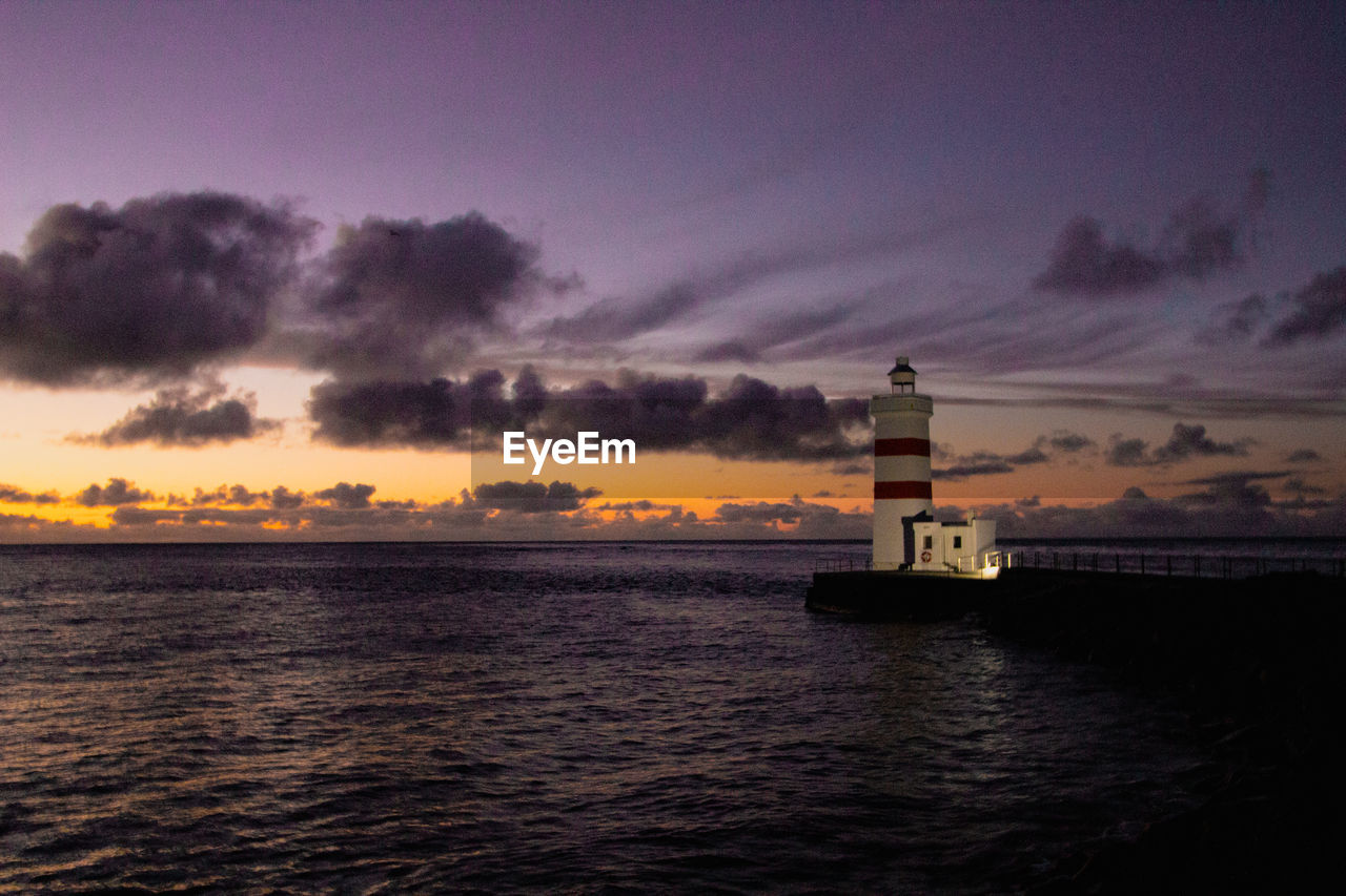 lighthouse, water, sky, sea, guidance, cloud, architecture, built structure, tower, sunset, building exterior, building, dawn, nature, ocean, horizon, evening, nautical vessel, scenics - nature, beach, beauty in nature, night, travel destinations, land, coast, no people, security, travel, protection, environment, tranquility, outdoors, transportation, horizon over water, coastline, landscape, reflection, silhouette, illuminated, dramatic sky, wave, ship, seascape