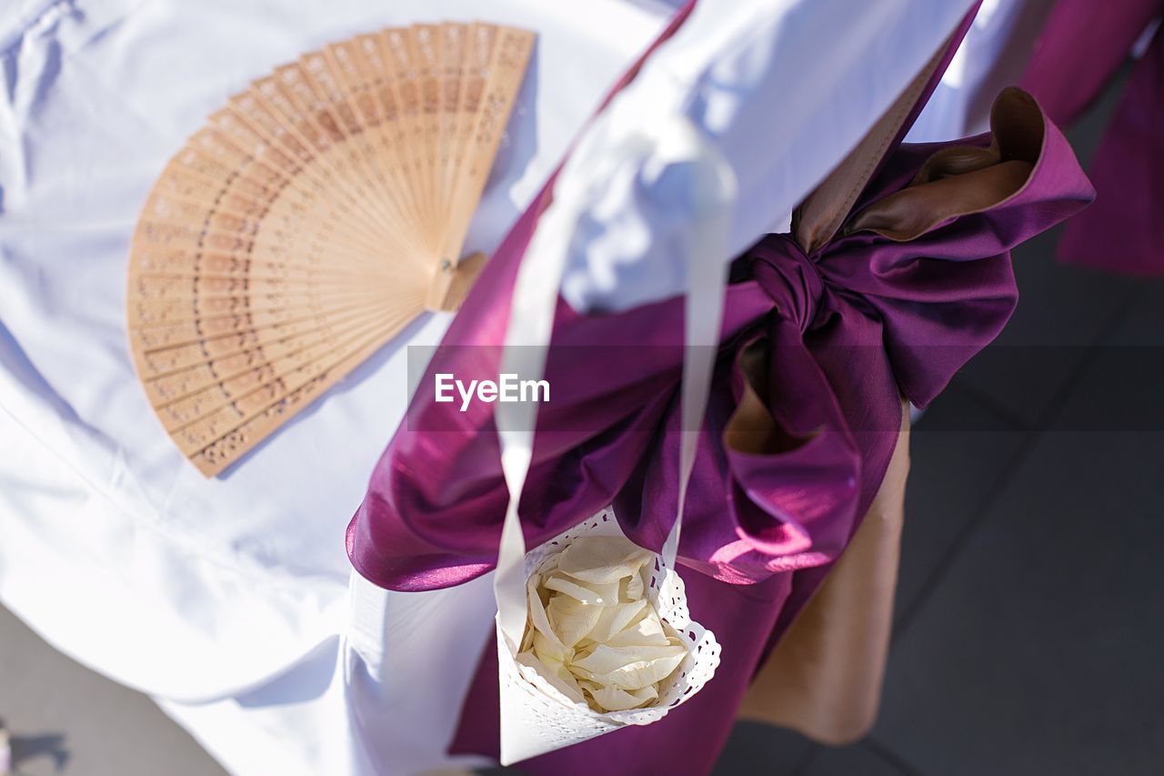 High angle view of decorated chair with folding fan and flower petals in bag