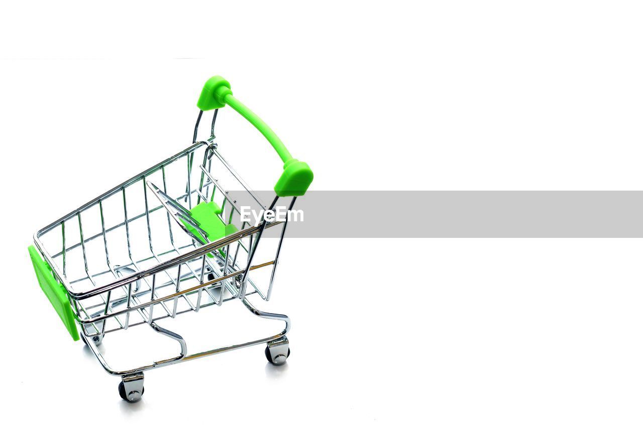 Close-up of miniature shopping cart over white background