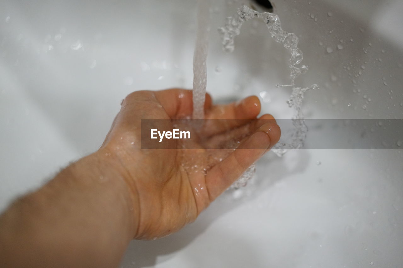 MIDSECTION OF PERSON HAND IN WATER