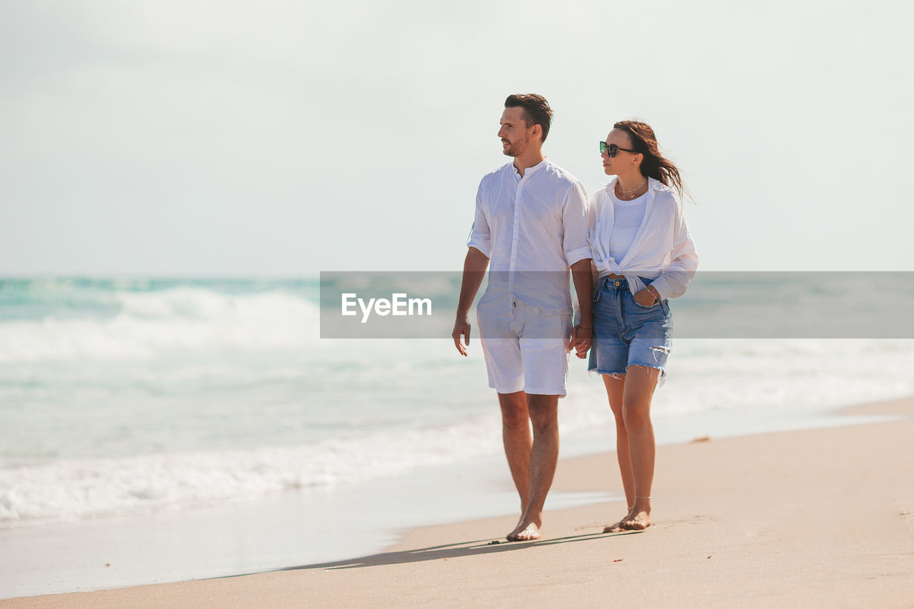 full length of couple standing at beach