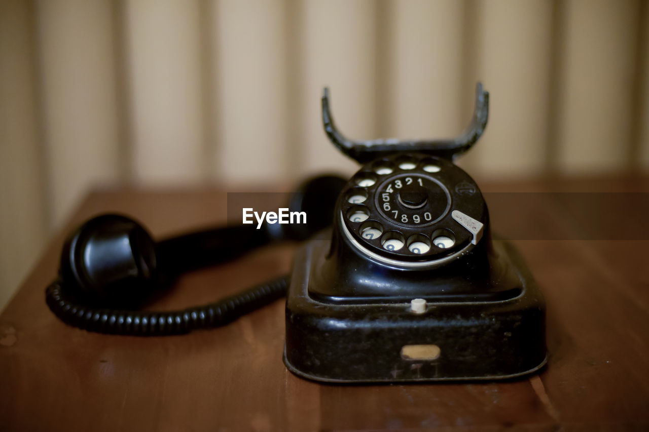 corded phone, telephone, black, landline phone, rotary phone, indoors, communication, retro styled, telephone receiver, technology, table, history, no people, the past, nostalgia, focus on foreground, close-up, old, number, iron