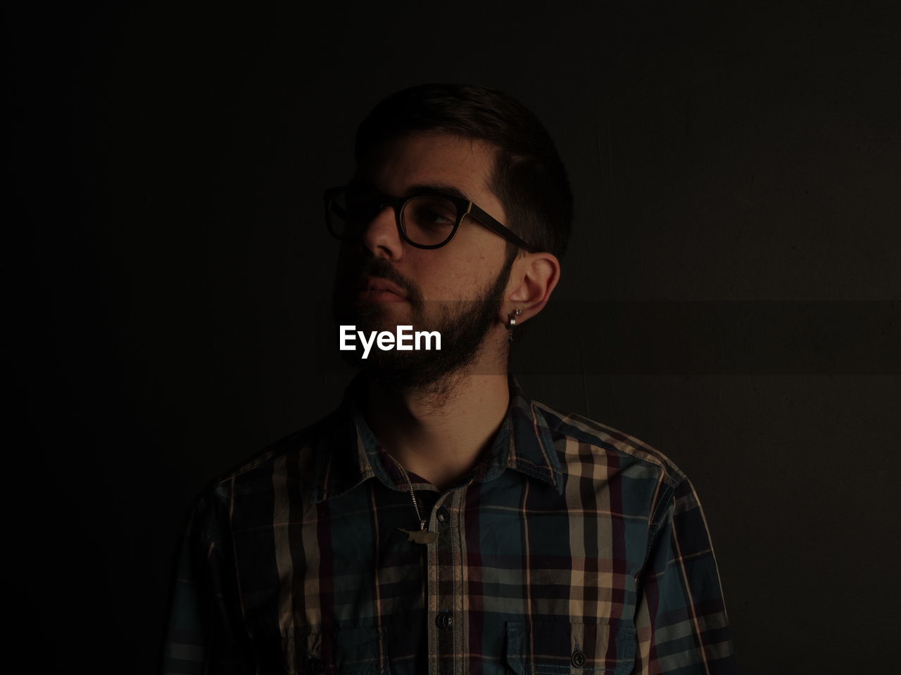 Young man wearing eyeglasses against black background