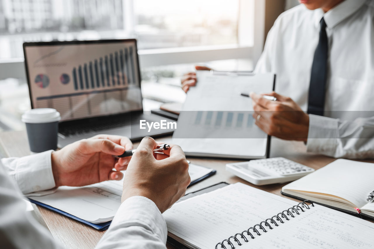 midsection of business colleagues working on table