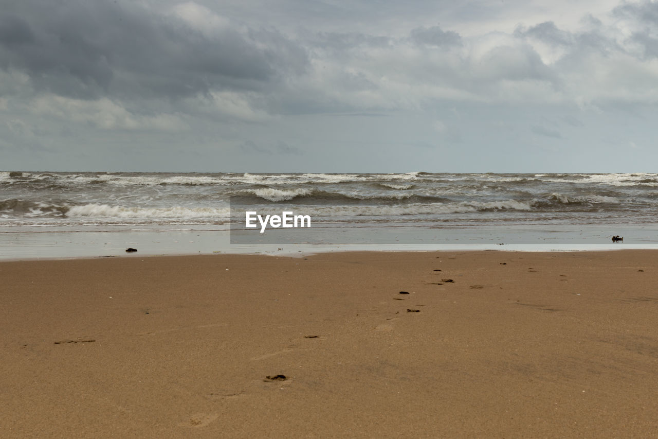 Scenic view of beach and sea against cloudy sky