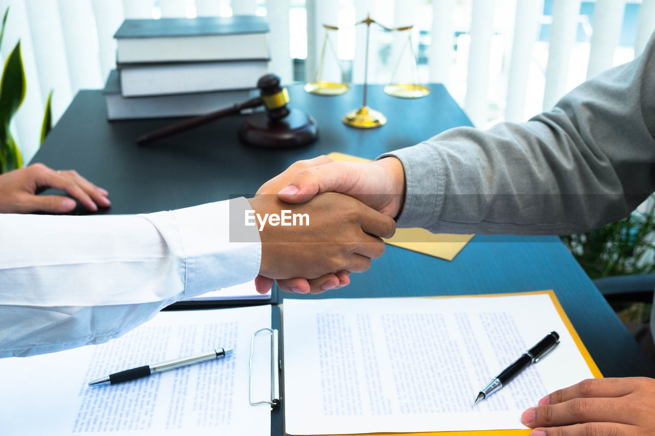 MIDSECTION OF MAN WORKING ON TABLE WITH PAPER