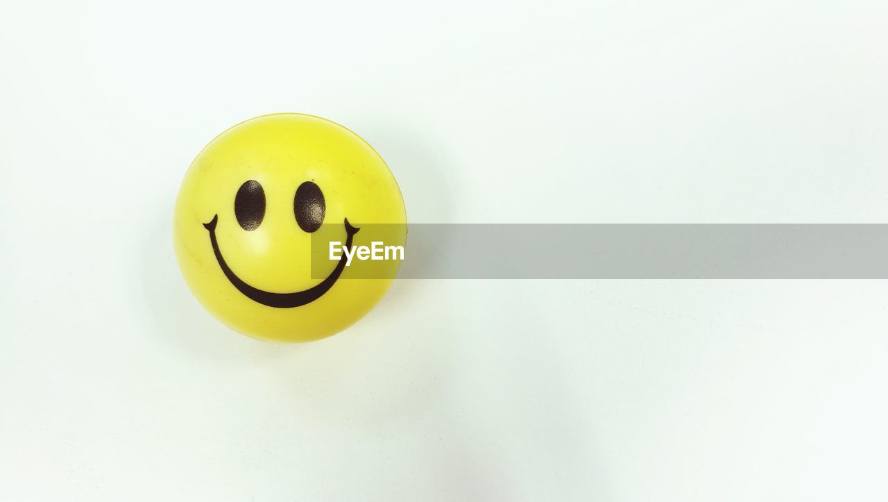 High angle view of yellow anthropomorphic smiley face on white background