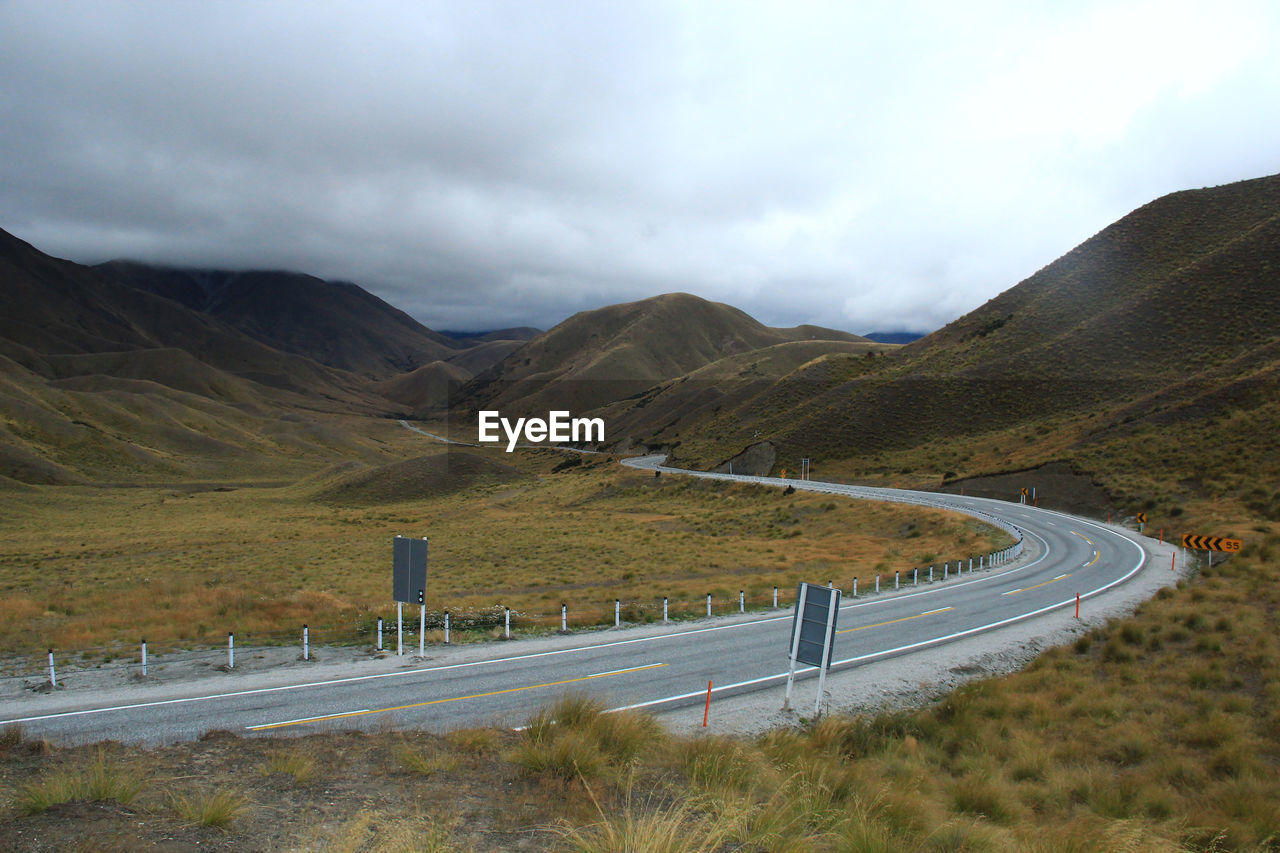 Scenic view of road by mountains against sky