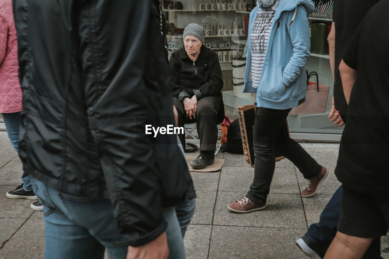 REAR VIEW OF PEOPLE STANDING ON STREET