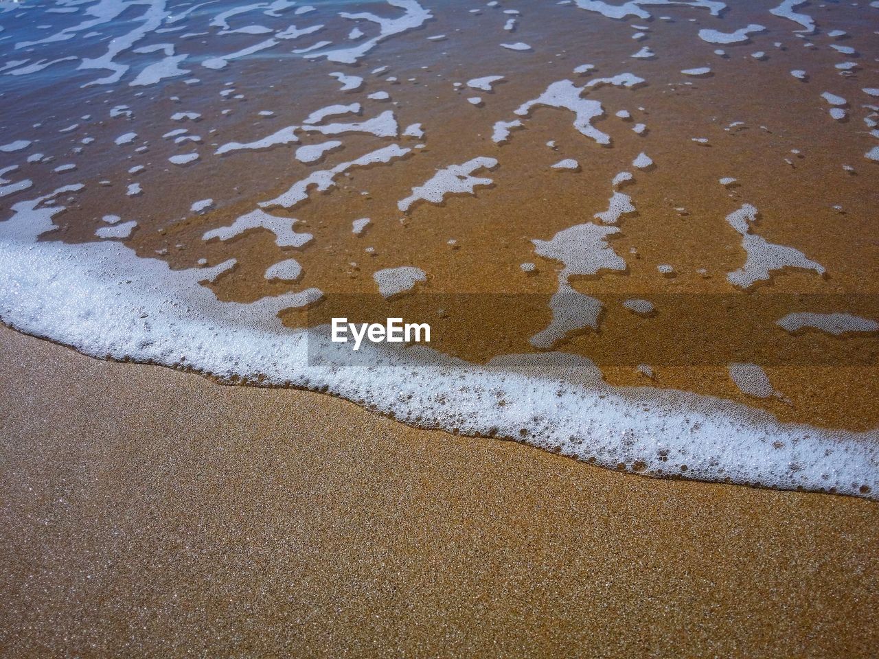 High angle view of water and sand on sunny day at beach