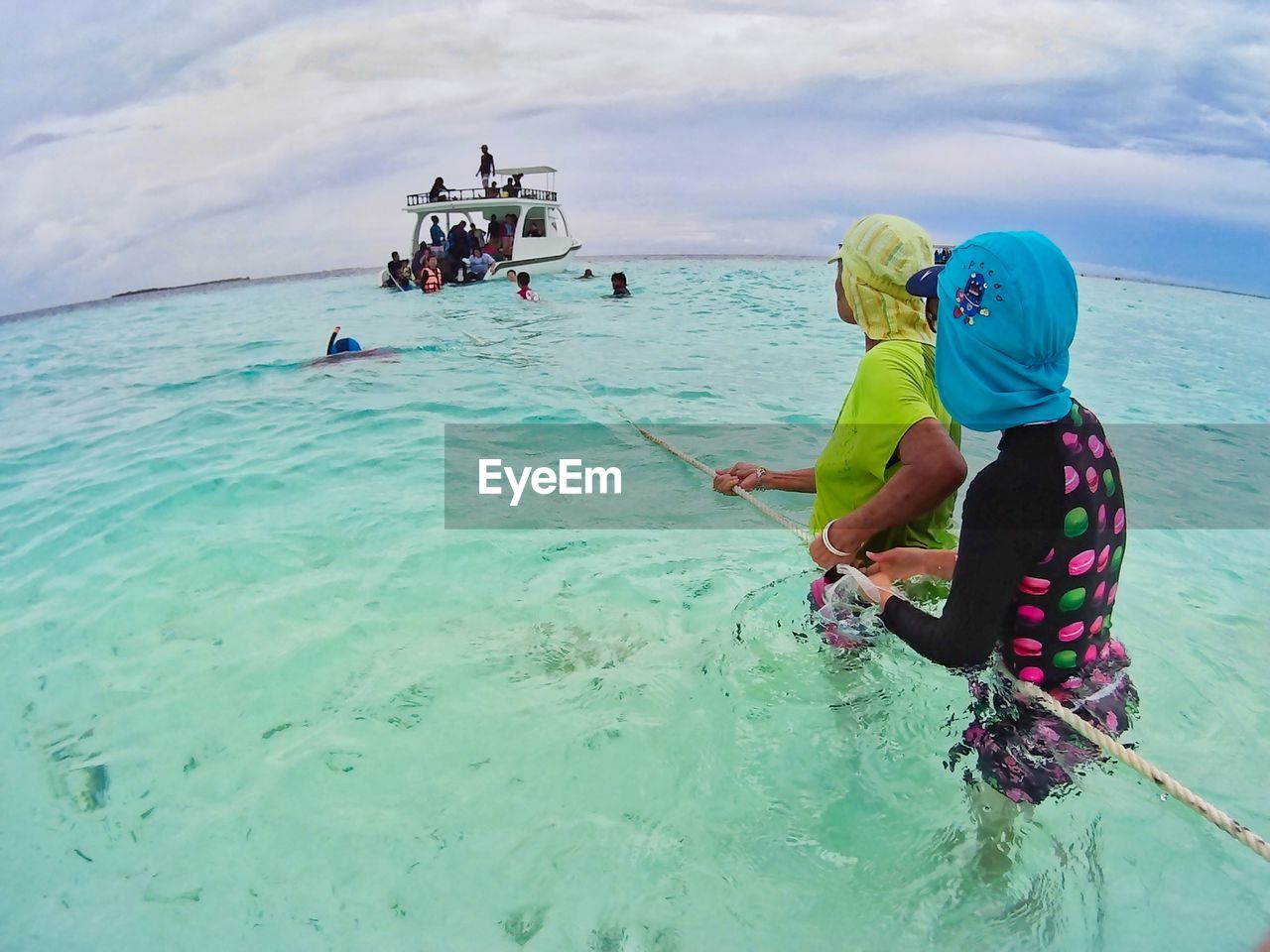 PEOPLE STANDING ON SHORE AGAINST SKY