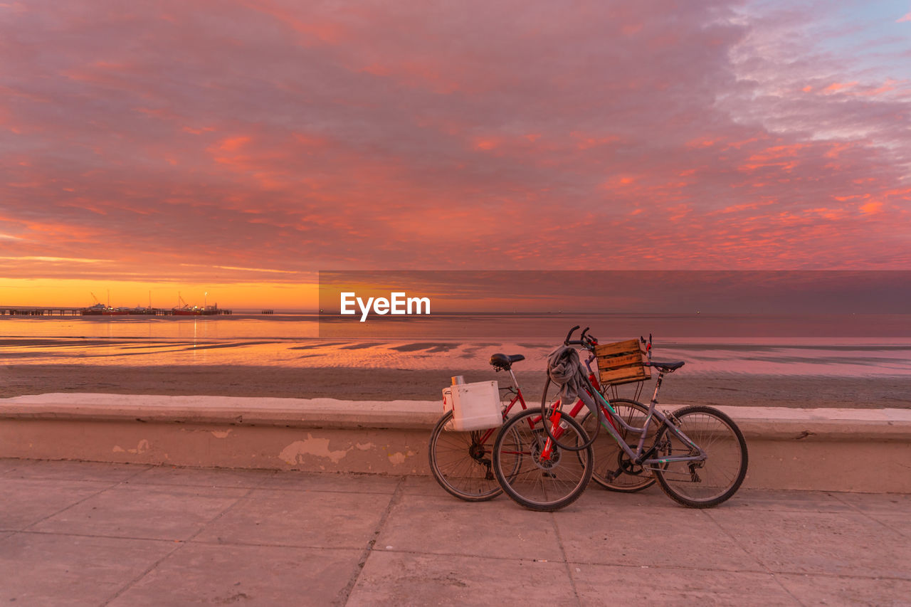 sky, sunset, transportation, bicycle, water, sea, cloud, beach, nature, mode of transportation, land, orange color, beauty in nature, travel, scenics - nature, activity, horizon, horizon over water, coast, sand, land vehicle, shore, tranquility, sports, vehicle, dusk, environment, travel destinations, dramatic sky, evening, outdoors, landscape, tranquil scene, cycling, tourism, holiday, lifestyles, sports equipment, vacation, city, motion, trip, sunlight, adult
