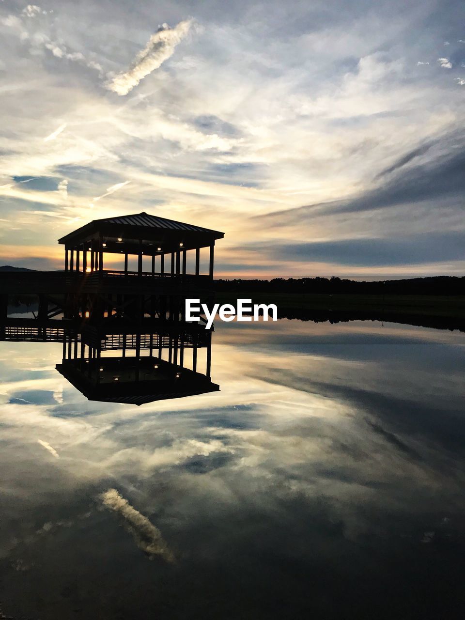 Pier on lake against sky during sunset