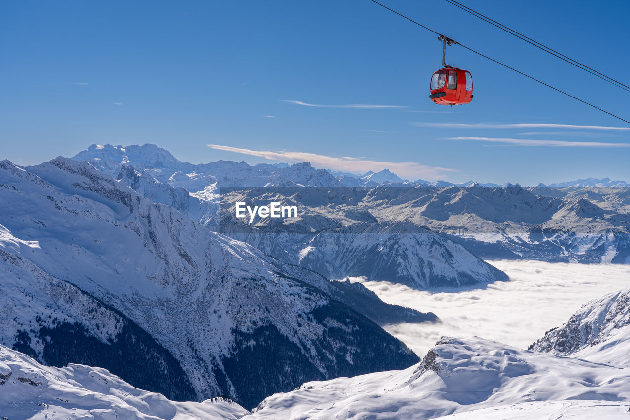 Red gondola of cable car seen from bellecote glacier, la plagne, france. inversion clouds in valley