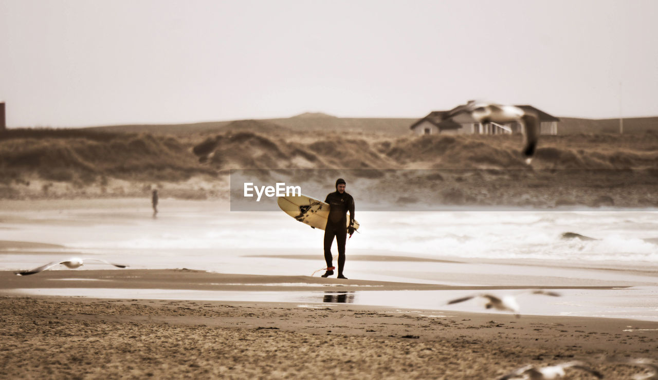 REAR VIEW OF MAN STANDING ON SHORE