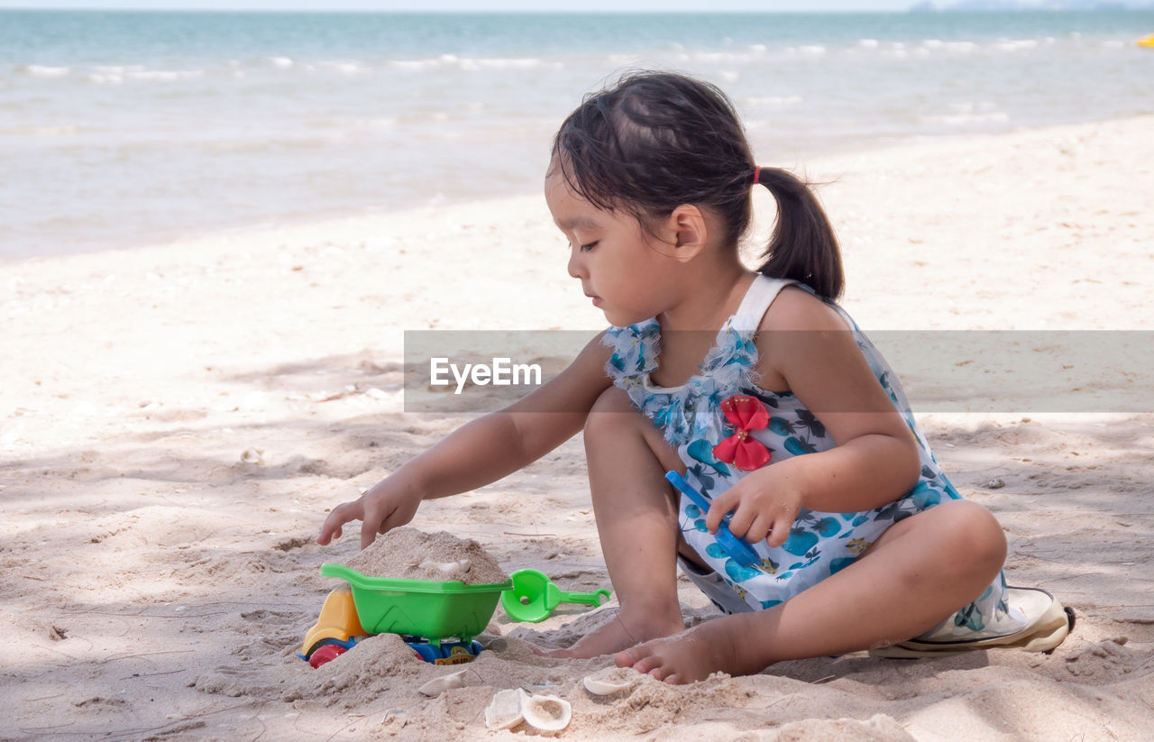Girl playing with toys at beach