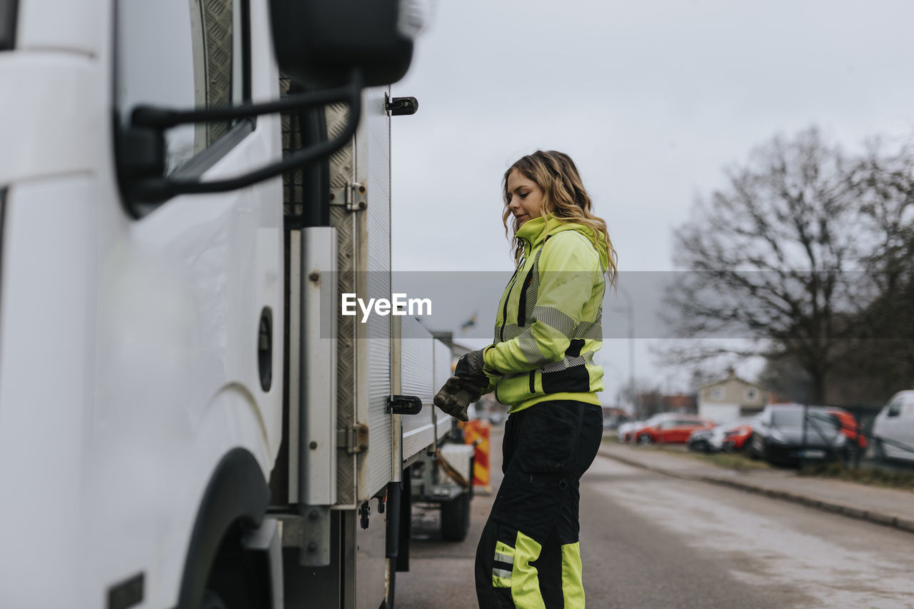 Female road worker standing next to truck