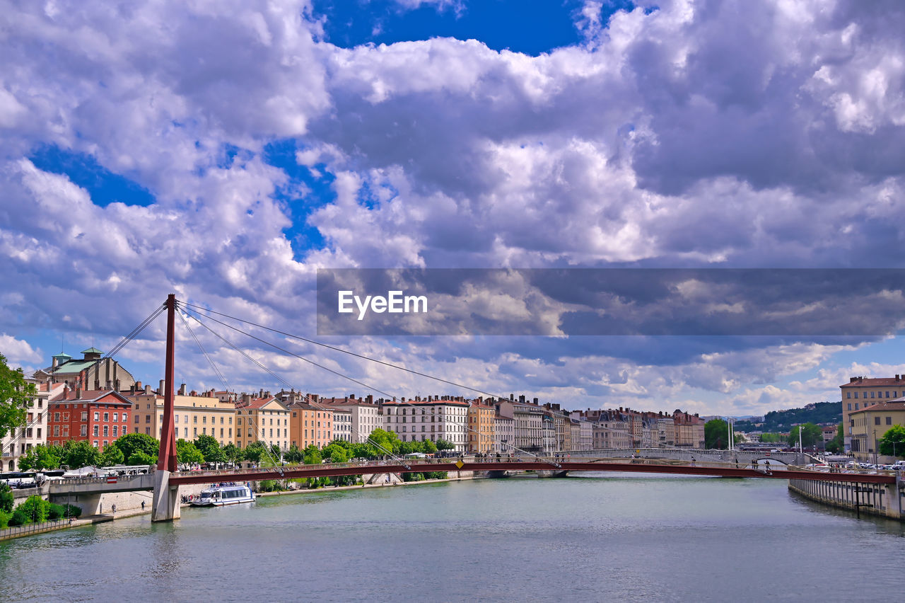 BRIDGE OVER RIVER AGAINST CLOUDY SKY