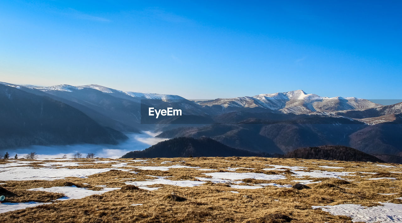 Scenic view of snowcapped mountains against clear blue sky