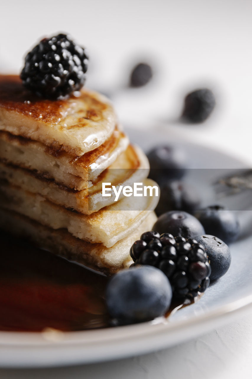 Close up of a fluffy homemade pancakes with syrup and berries