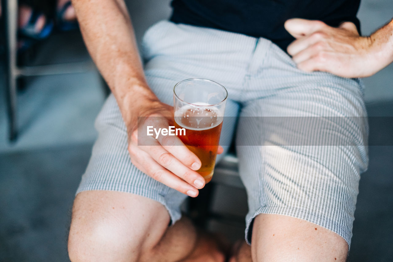 Midsection of man holding beer glass