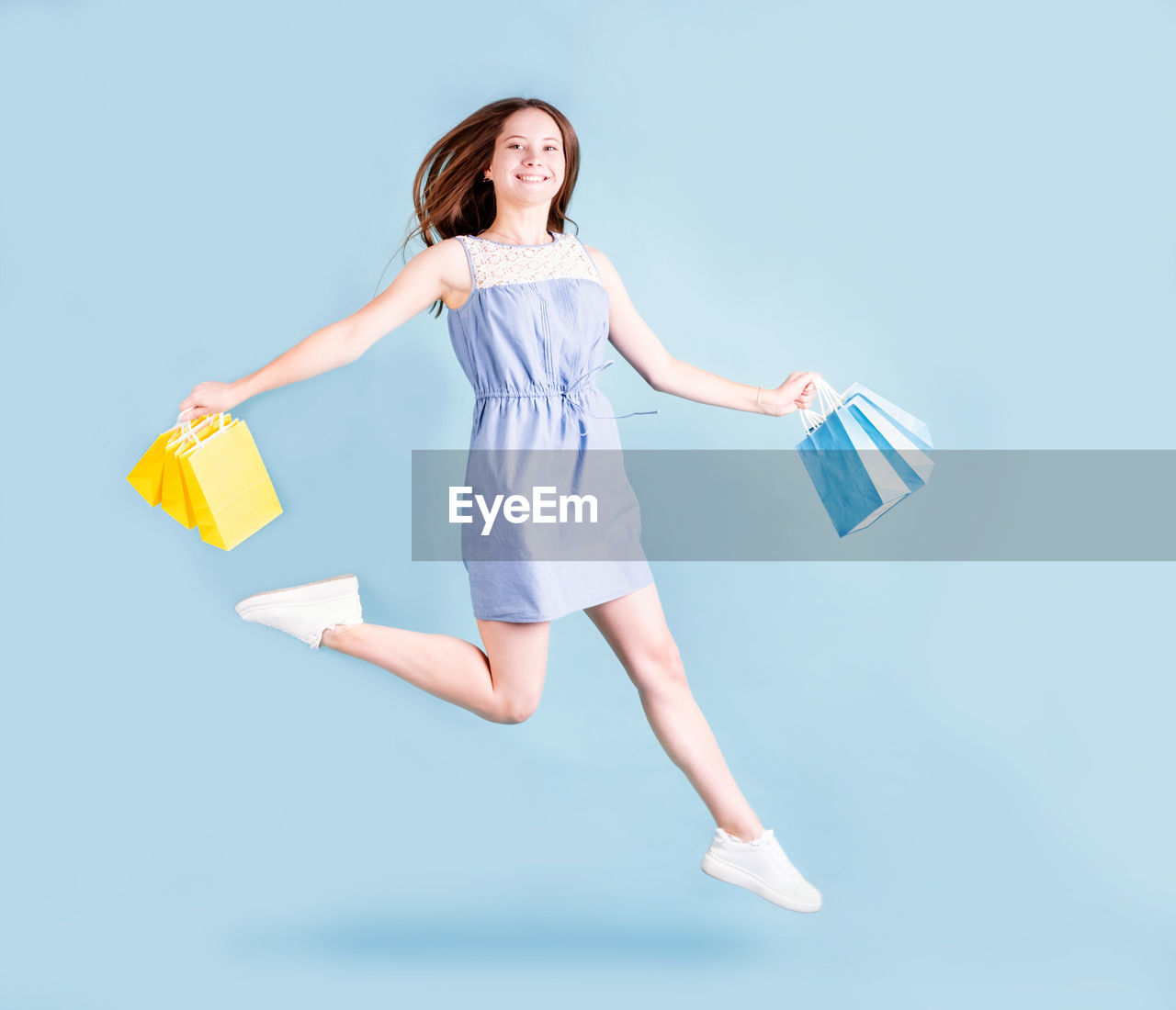 Shopping woman. cheerful young woman running and jumping holding shopping bags. full length 