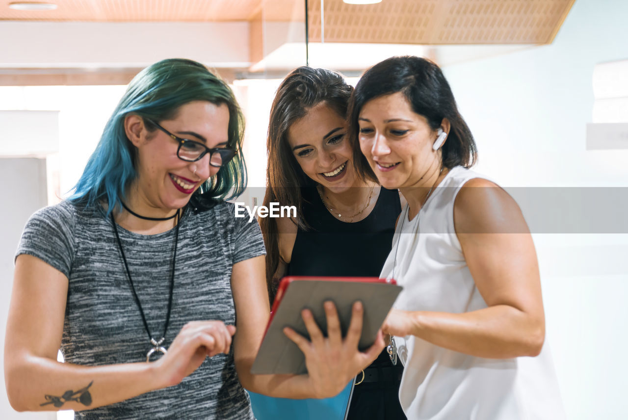 3 young women are looking at a tablet