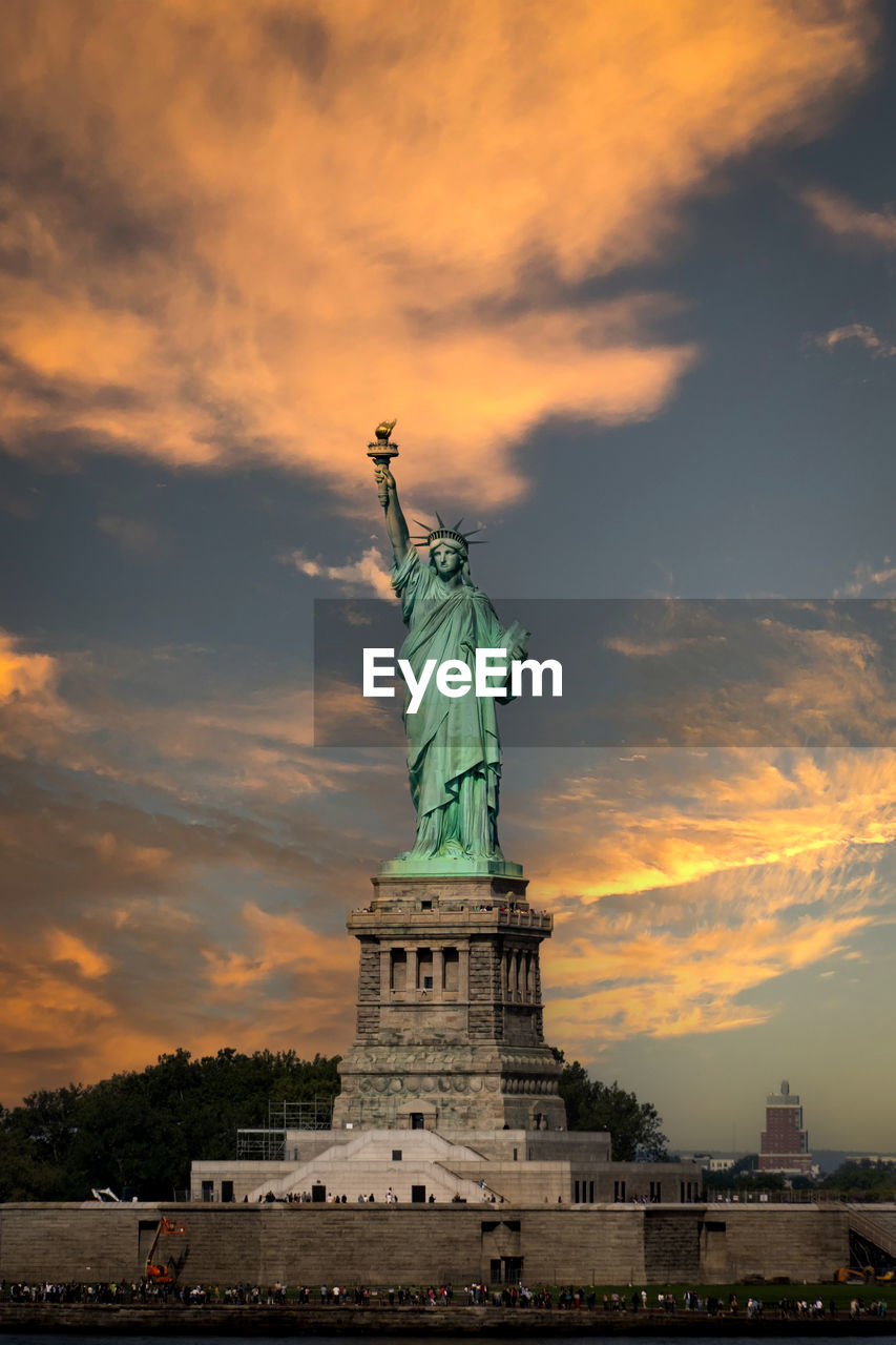 Vertical landscape of statue of liberty with dramatic sunset