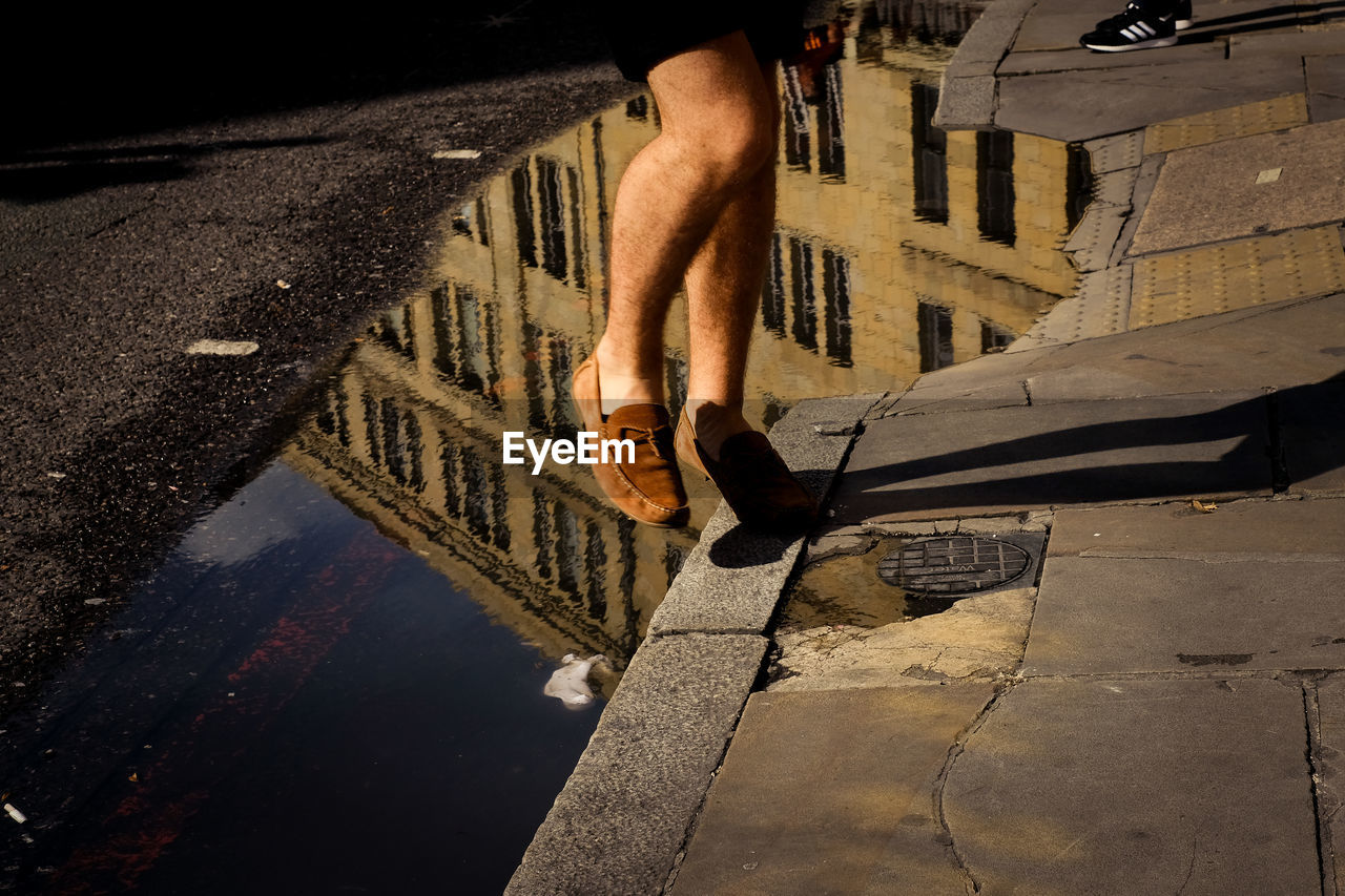 Low section of man in puddle on street