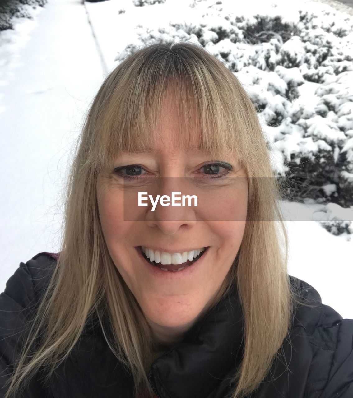 PORTRAIT OF SMILING WOMAN WITH SNOW