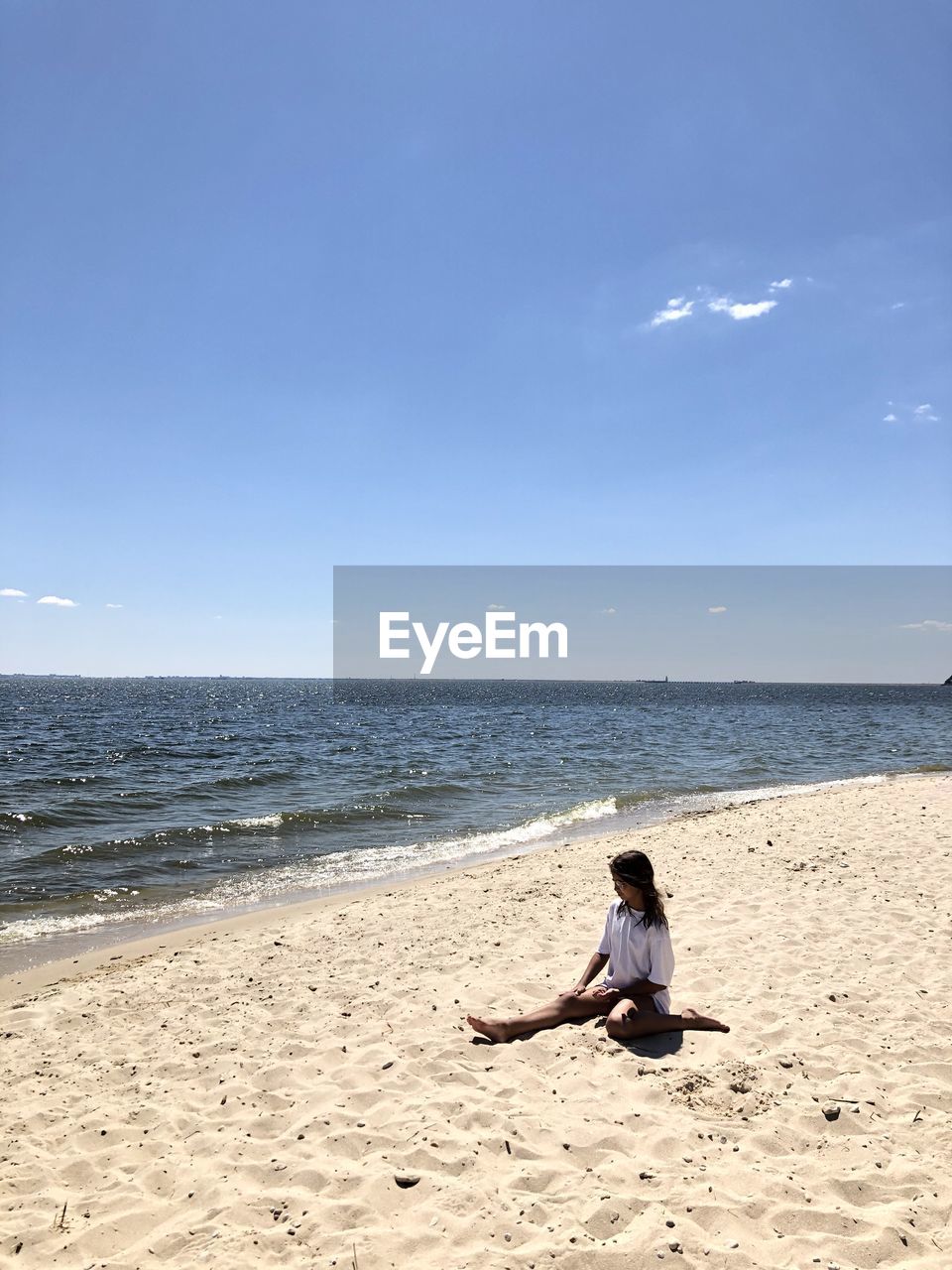 Woman sitting on beach against sky