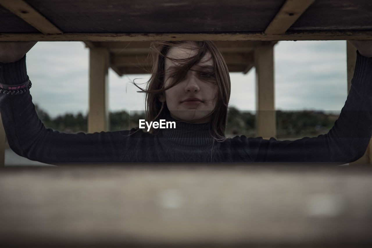 portrait of young woman looking away while standing by railing