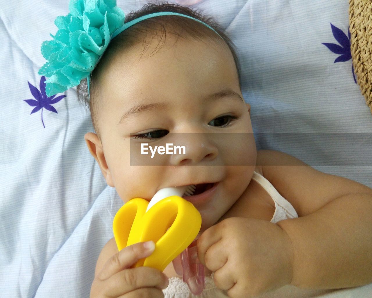 Close-up of cute baby biting toy while lying on bed