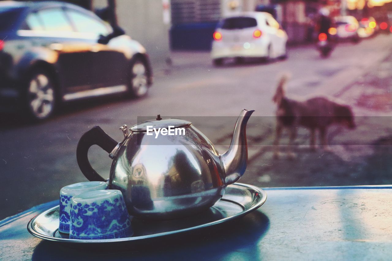 Close-up of teapot and cups in plate on table at sidewalk cafe