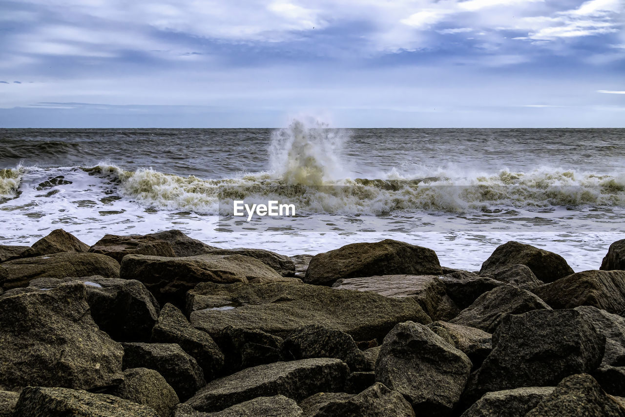 SCENIC VIEW OF ROCKY BEACH AGAINST SKY