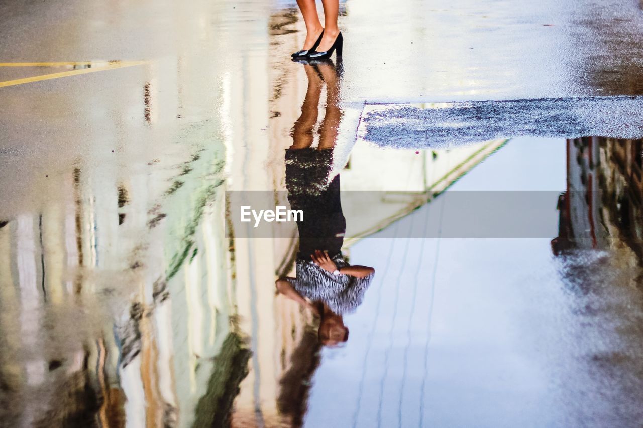 LOW SECTION OF PERSON STANDING ON WET SHORE