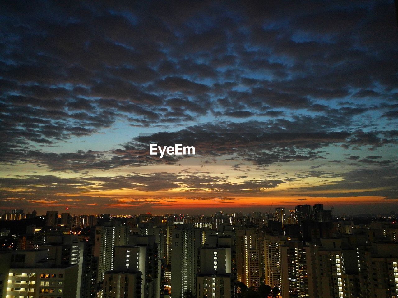 Cityscape against cloudy sky during sunset