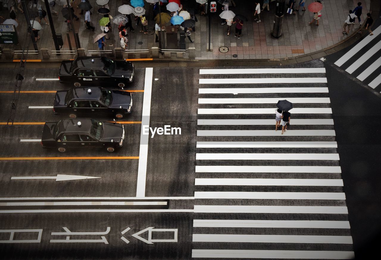 High angle view of people holding umbrella while walking on city street