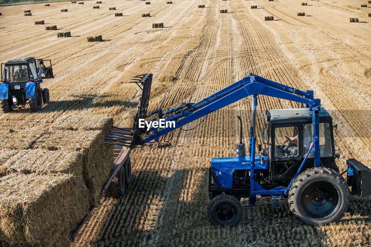 High angle view of tractor with hay bales on field