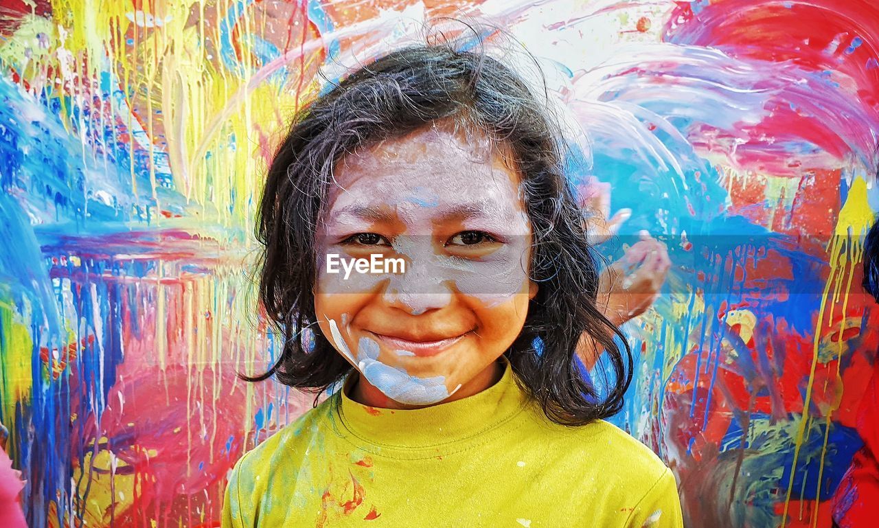 PORTRAIT OF SMILING GIRL WITH MULTI COLORED FACE