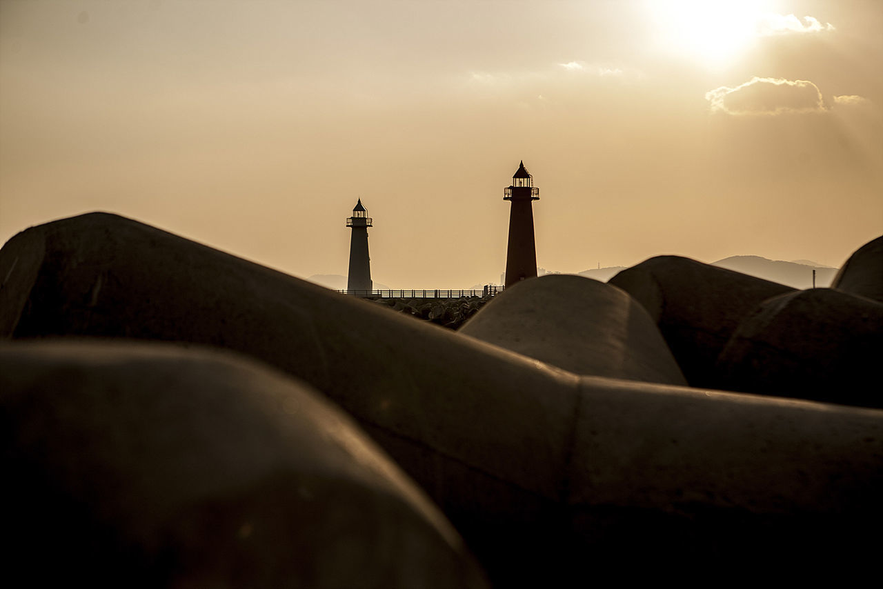 Lighthouses in front of tetrapod rocks during sunset