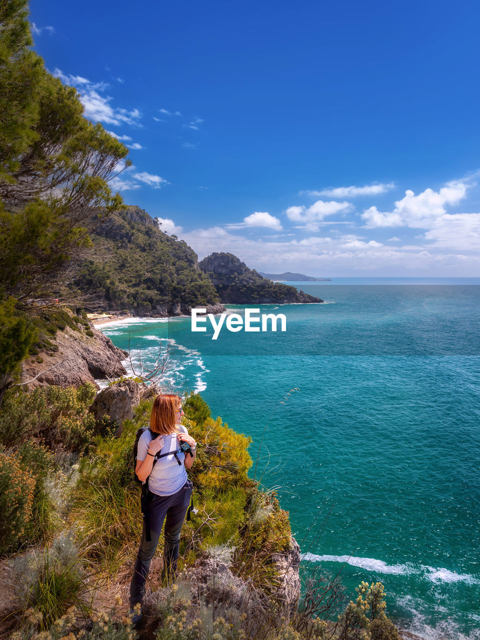 Rear view of woman standing by sea against sky