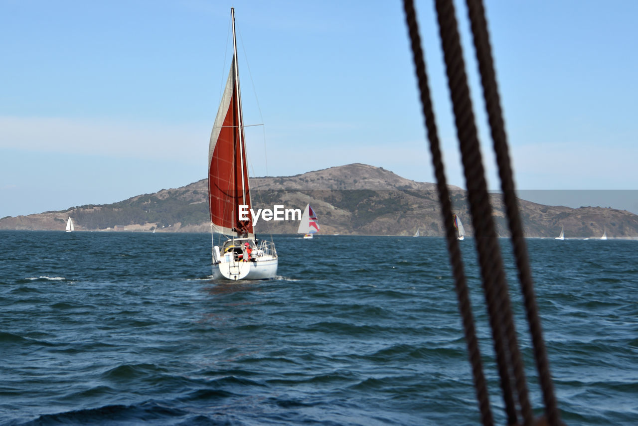 SAILBOATS SAILING IN SEA AGAINST SKY