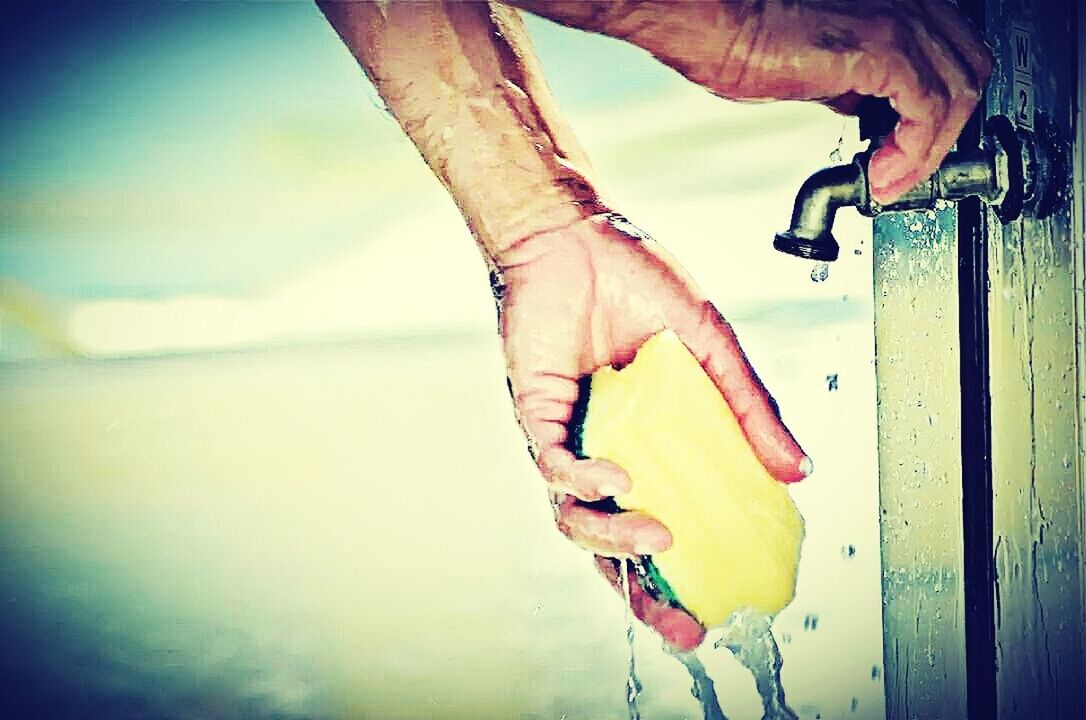 Close-up of hand washing object under tap