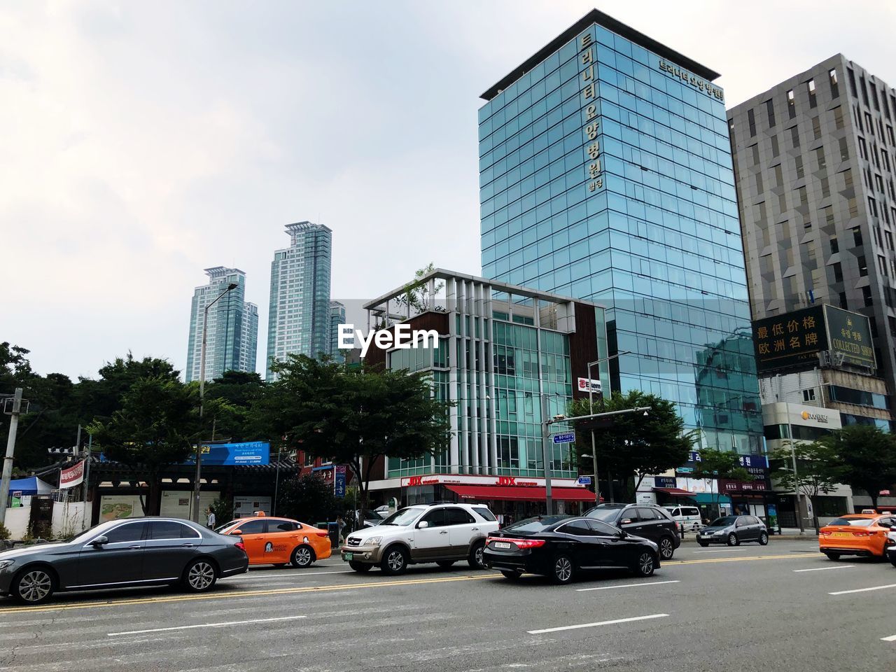 TRAFFIC ON ROAD BY BUILDINGS AGAINST SKY