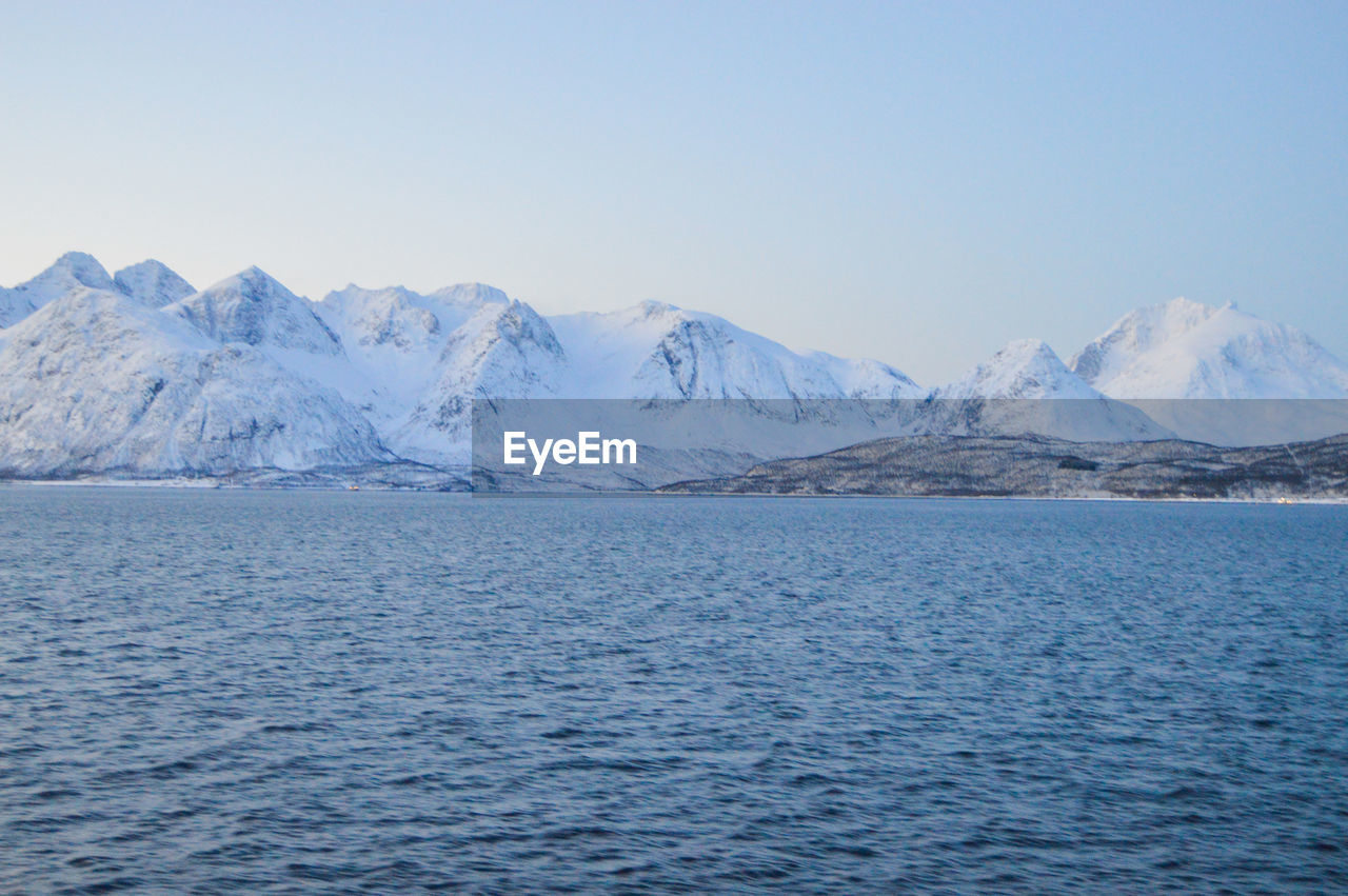 scenic view of sea and snowcapped mountains against sky