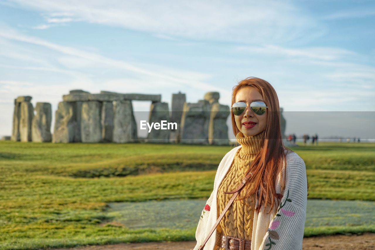 Portrait of woman standing at stonehenge against sky