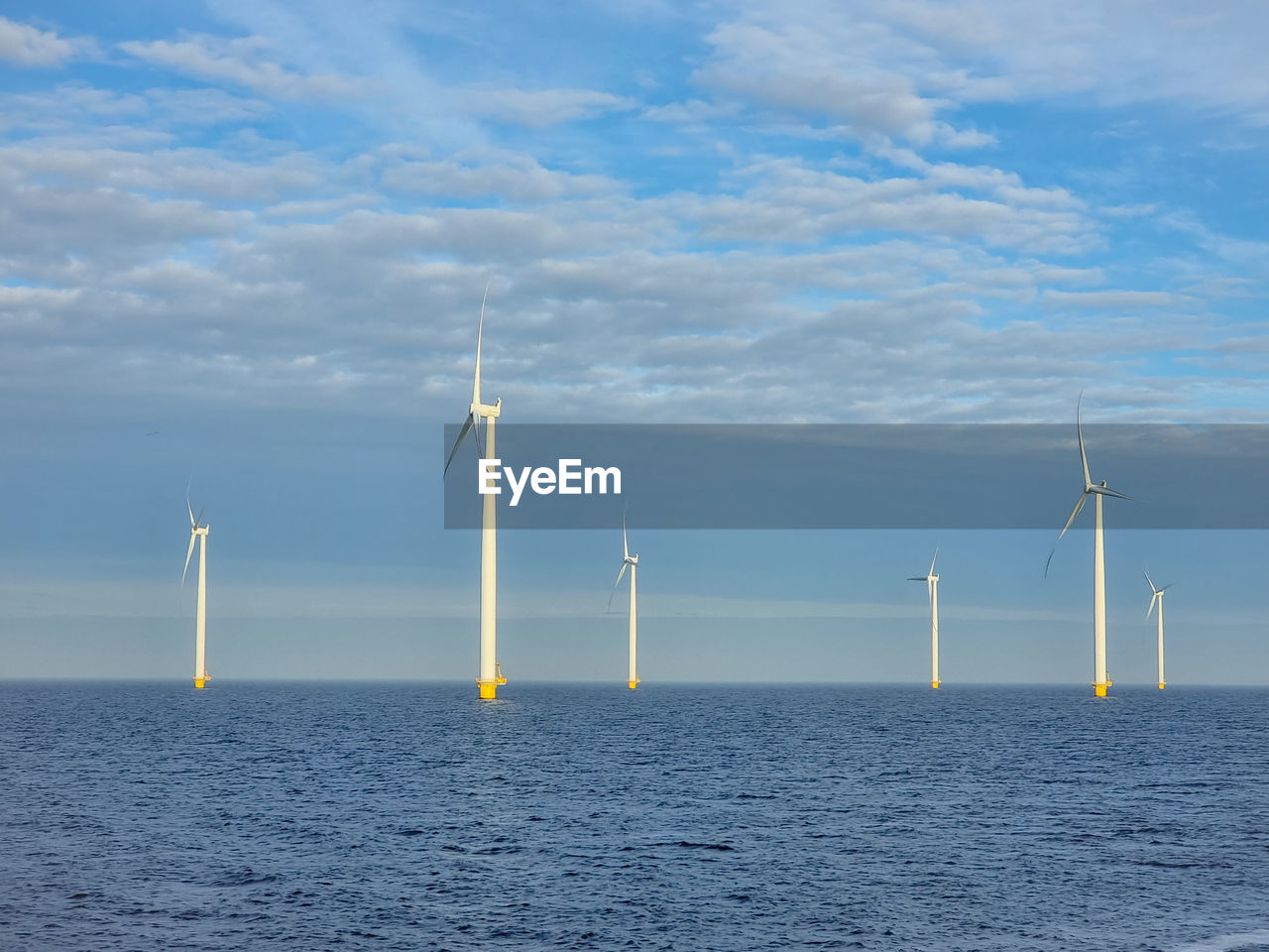 Wind turbines in sea against sky